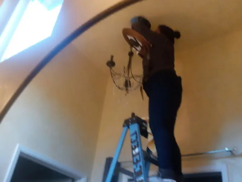 Electrician installing a chandelier in a Allendale residence